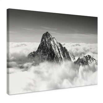Leinwandbild Bergspitze über den weißen Wolken 
